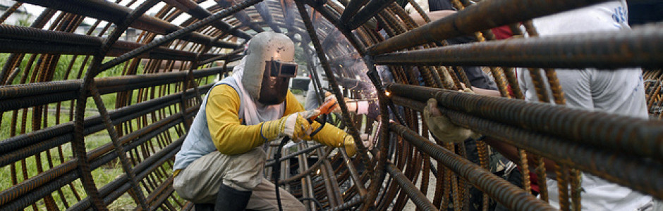 Man working inside a large reinforced steel tube. Philippines.